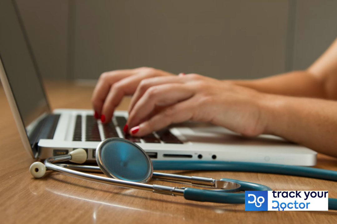 A doctor typing on a laptop with a stethoscope.